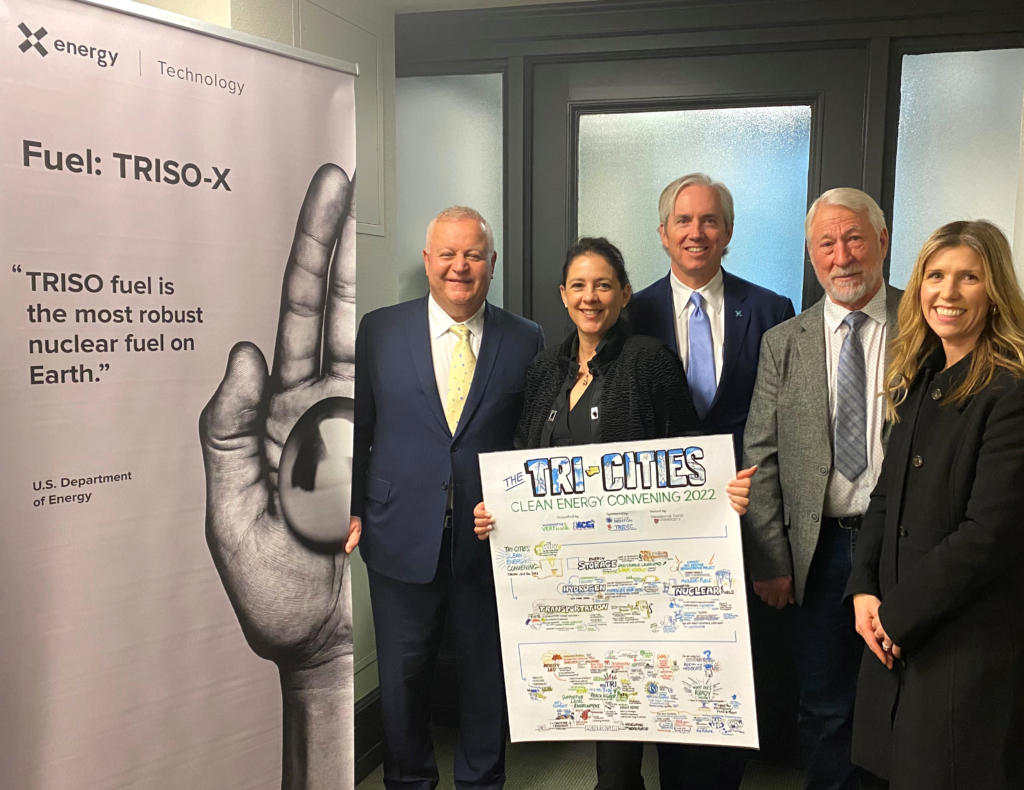 Three white men and two white women stand smiling with one of the women holding a hand drawn infographic with the title of Tri-Citites at the top.